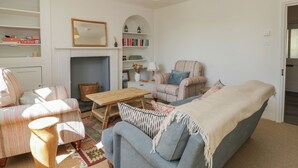 A living room with a sofa, armchairs, a coffee table, a fireplace, and a bookshelf. - Middle Cottage (Salisbury)