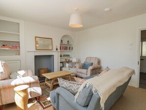 A living room with a sofa, armchairs, a coffee table, a fireplace, and a bookshelf. - Middle Cottage (Salisbury)