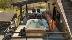 Een hottub op een terras met buitenmeubilair, een pergola en uitzicht op het omliggende landschap.