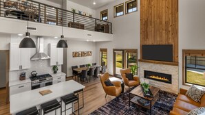 Een ruime woonkamer met een open haard, een eethoek en een keuken met een hoge plafon en modern design.