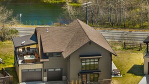 Een modern huis met twee verdiepingen, een garage, een hottub op het terras en uitzicht op een meer.