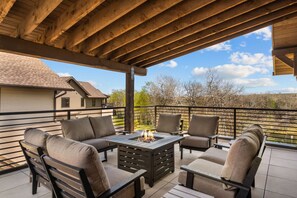 A covered patio with outdoor furniture, a fire pit, and a view of a residential area.