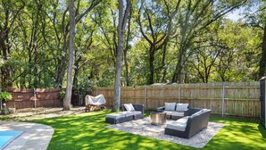 Un giardino con piscina, un'area relax coperta e una recinzione in legno.