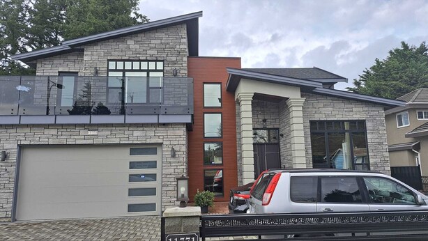 A modern two-story house with a garage, large windows, and a vehicle parked in the driveway.