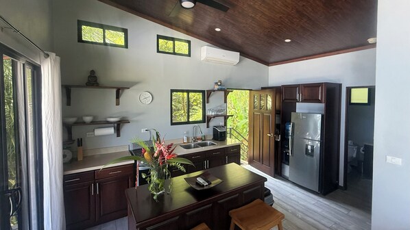 Una cocina moderna con armarios de madera oscura, un refrigerador de acero inoxidable y una isla grande con un florero.