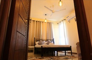 Ein Schlafzimmer mit Bett, Vorhängen, Deckenventilator und Nachttisch.
