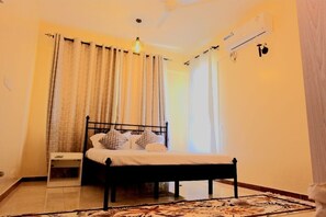 Ein Schlafzimmer mit Bett, Vorhängen, Nachttisch und Deckenventilator.