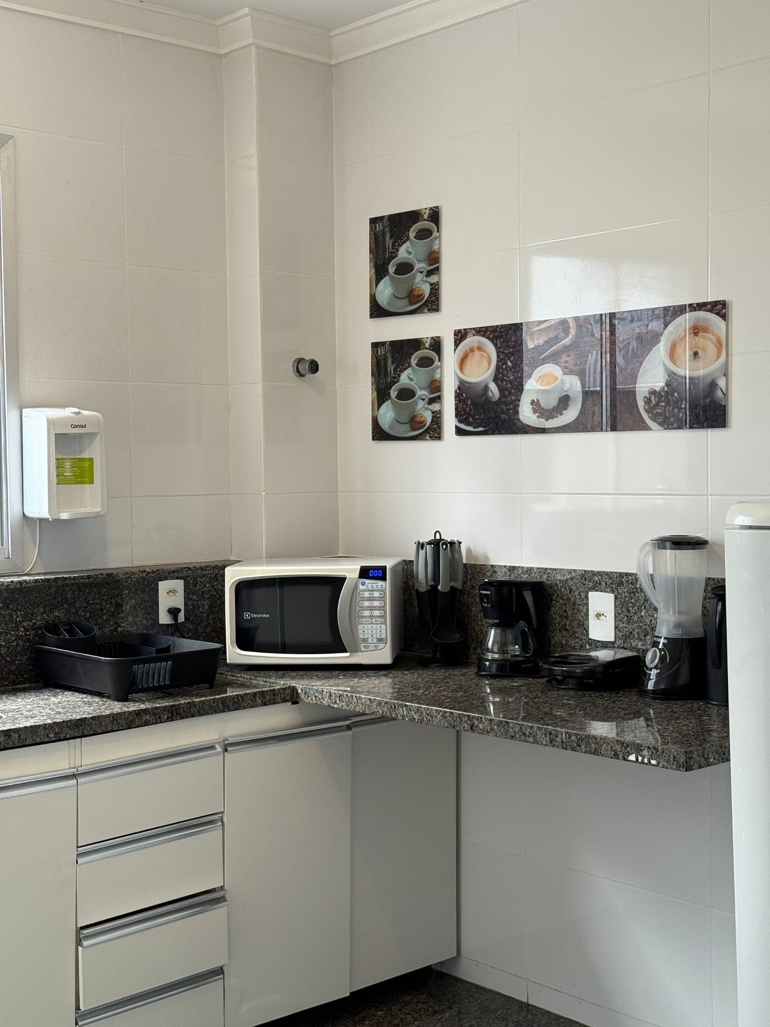 Una cuina moderna amb microones, cafetera i batedora al taulell.