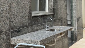 Moderni keittiö, jossa on graniittitasot, ruostumattomasta teräksestä valmistettu pesuallas ja ikkuna, jossa on sälekaihtimet.