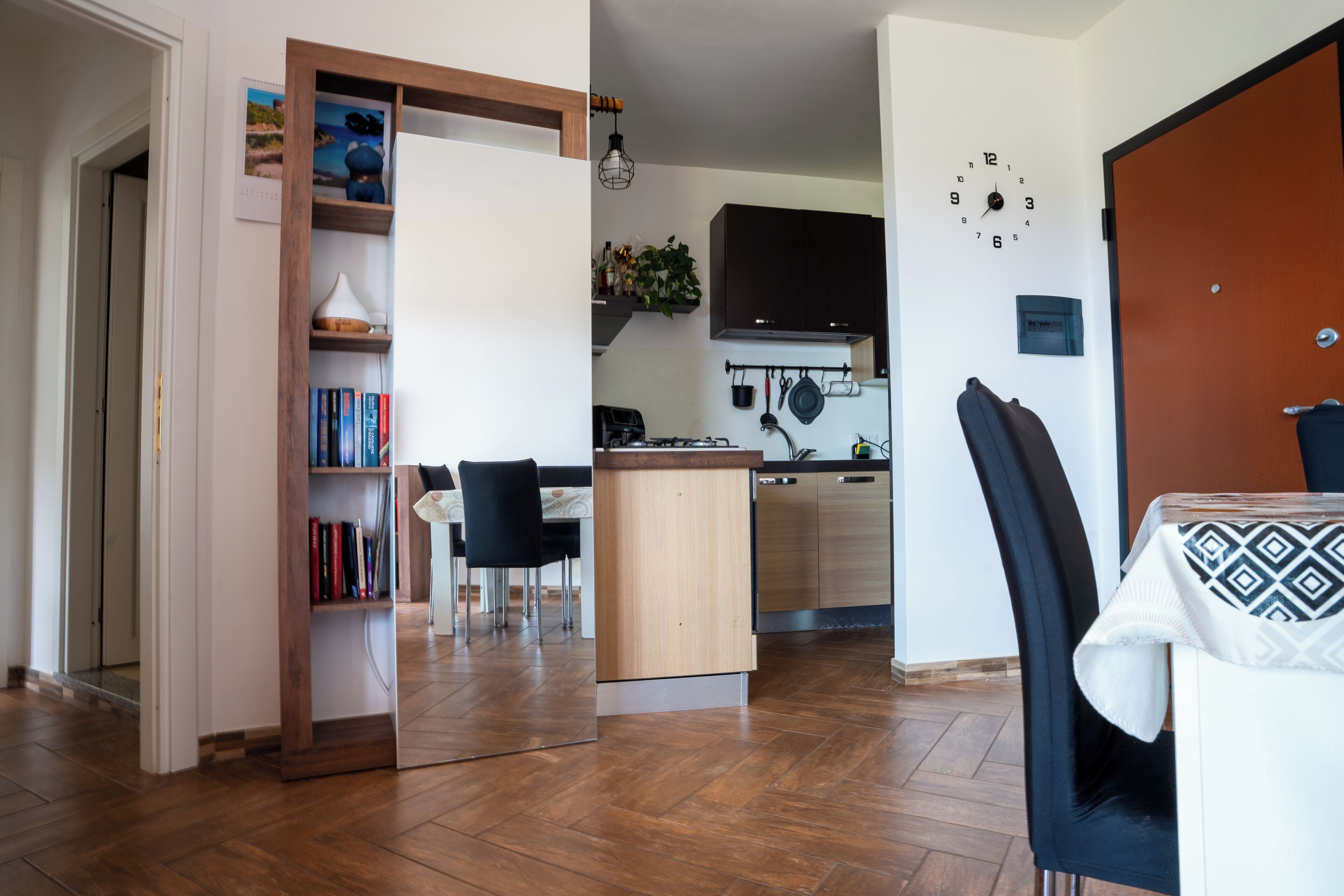 Une cuisine moderne équipée d’un lave-vaisselle intégré, un coin repas avec une table et des chaises, et une bibliothèque.