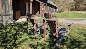 A rustic building with a porch and wooden chairs.