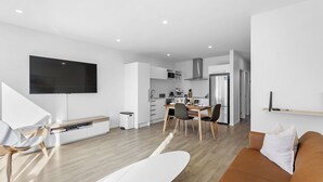 Een moderne keuken met een eethoek, een flatscreen televisie en een bank.