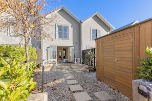 Ein zweistöckiges Haus mit überdachter Terrasse, Holzzaun und Kiesweg.