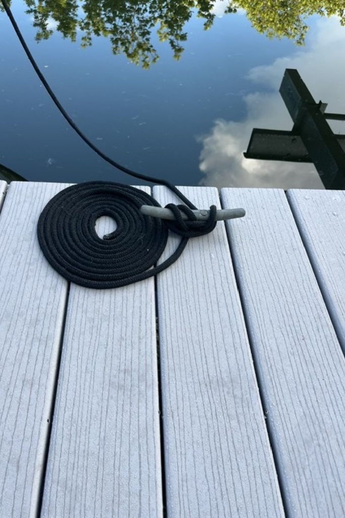 Ein schwarzes, aufgewickeltes Kabel auf einer Holzbodenfläche.