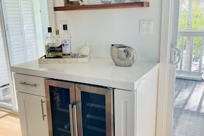 Una cocina con encimera blanca, armarios de acero inoxidable y nevera con puerta de cristal.