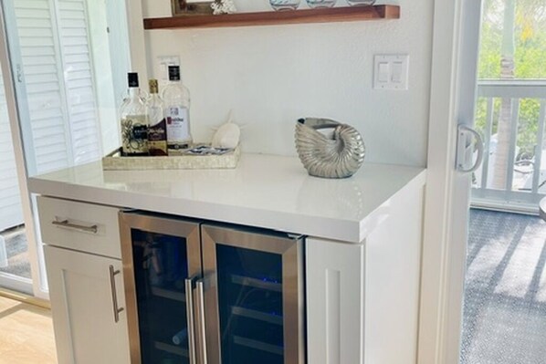 A kitchen with a white countertop, stainless steel cabinets, and a glass door refrigerator.