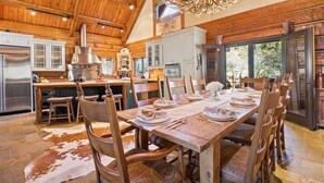 Una cocina amplia con armarios de madera, una isla grande y un comedor preparado para seis personas.