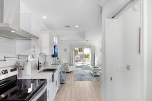 A modern kitchen with white cabinetry, a black stove, and a dining area with a blue patterned rug.