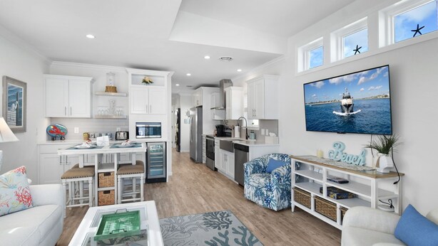 A modern living room with a dining area, kitchen, and a large TV displaying a boat on water.