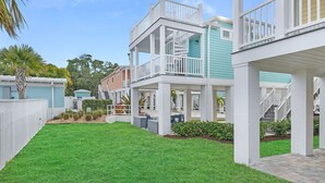 A multi-story residential building with a covered patio area, a fenced yard, and a clear sky.