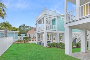 A multi-story residential building with a covered patio area, a fenced yard, and a clear sky.
