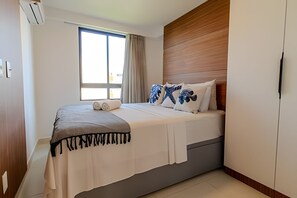 Una camera da letto con un letto, una finestra con tende, una testiera in legno e un armadio.