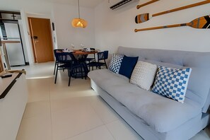 A modern living room with a sofa, dining table, chairs, and a hanging light fixture. - Dutra Ocean by MyFlats hospedagens (João Pessoa)