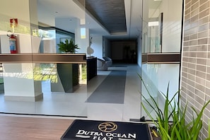 Un moderno vestíbulo de hotel con una recepción, una división de vidrio y vistas al exterior.