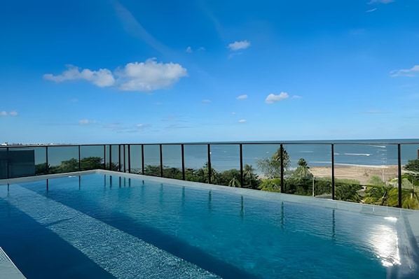 Una piscina infinita con vistas despejadas al océano y la playa.