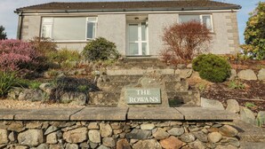 Una casa de piedra con un letrero que dice 'THE ROWANS'.