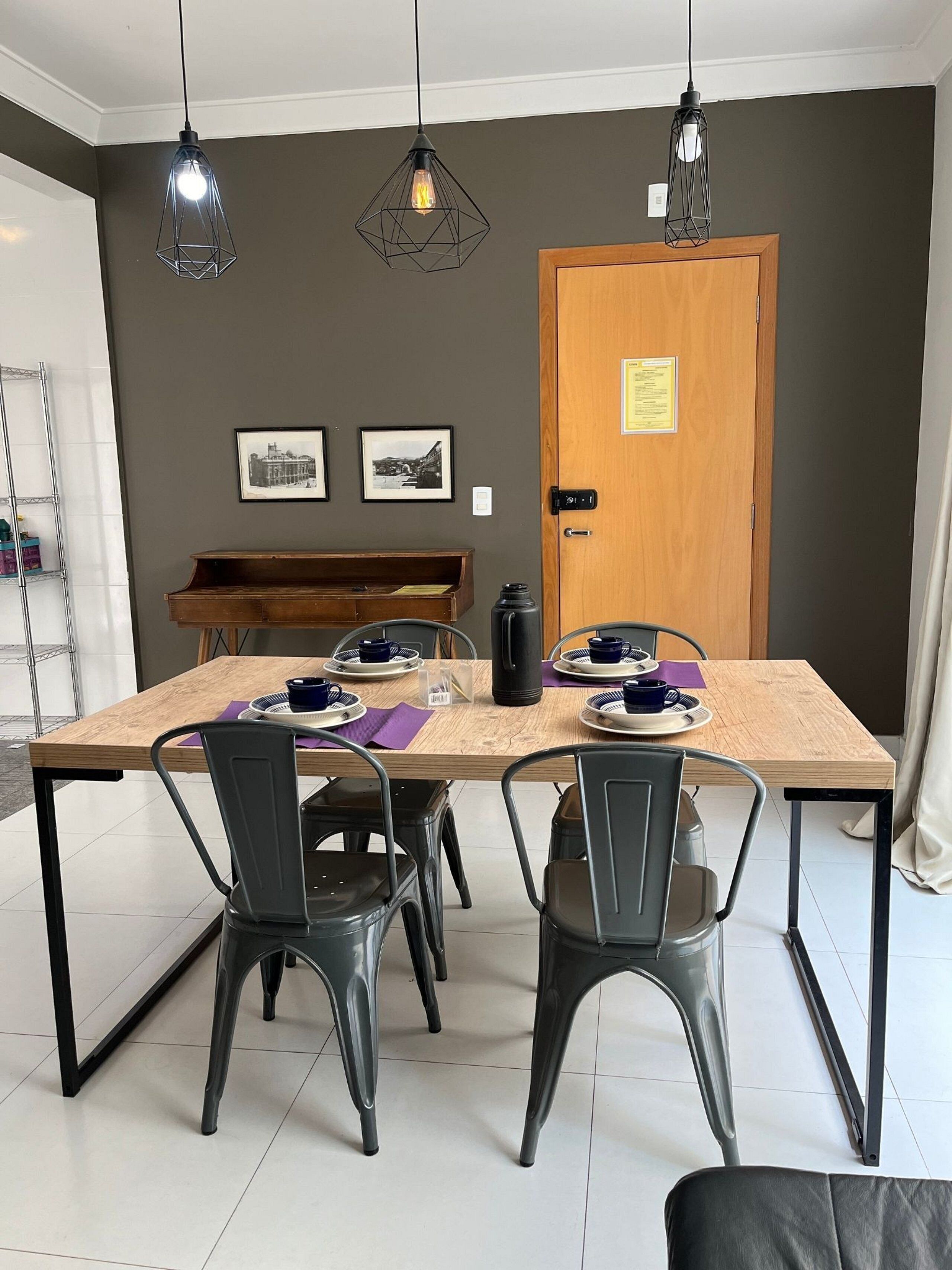 A dining area with a wooden table, four chairs, and two pendant lights.
