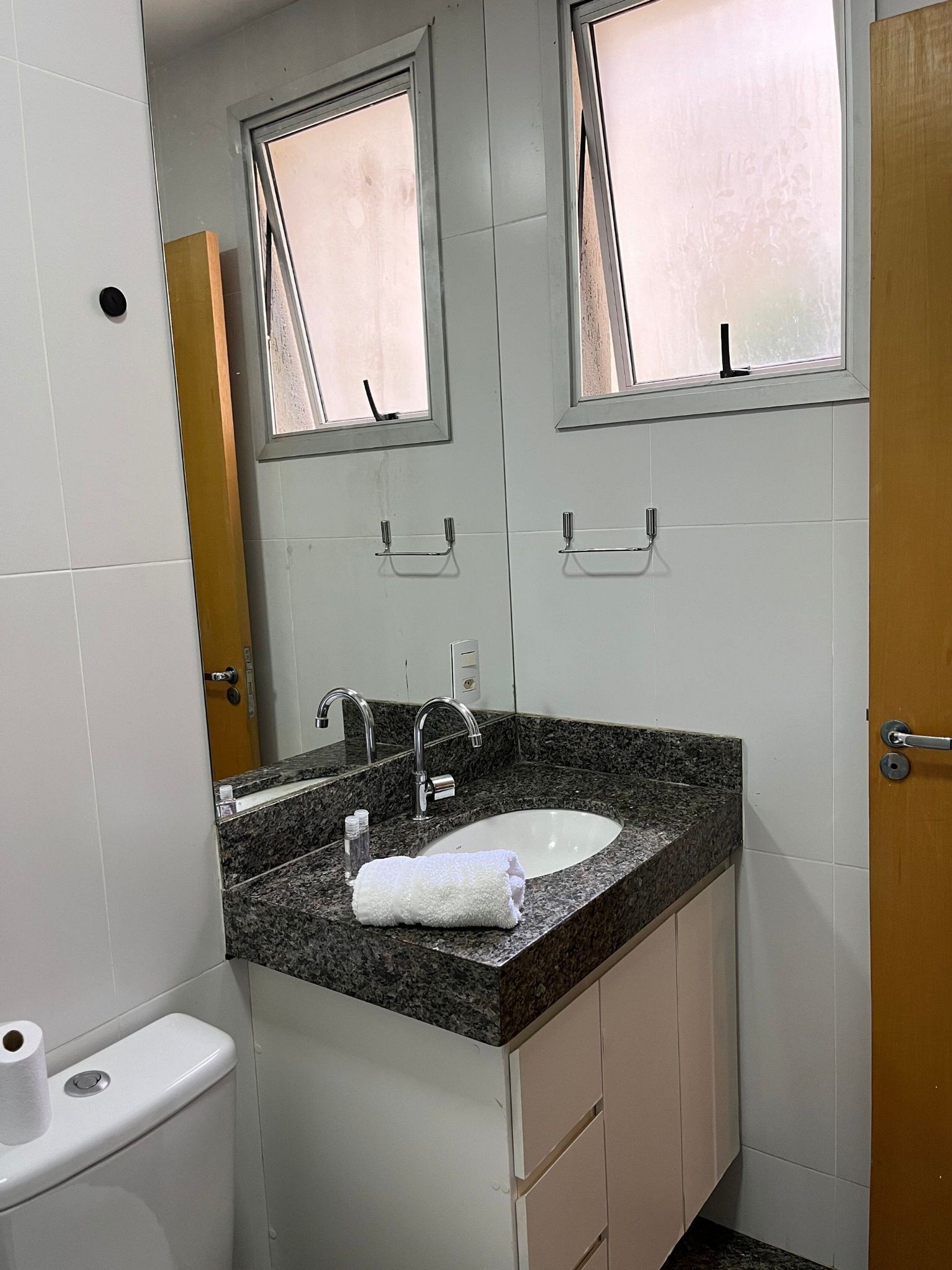 Een badkamer met een wastafel, spiegel en toilet.
