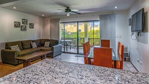 Un salon moderne avec un canapé, une table basse, un téléviseur et un balcon offrant une vue agréable.