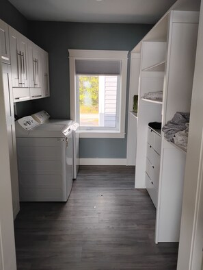A laundry room with a washing machine, dryer, and a window with blinds.