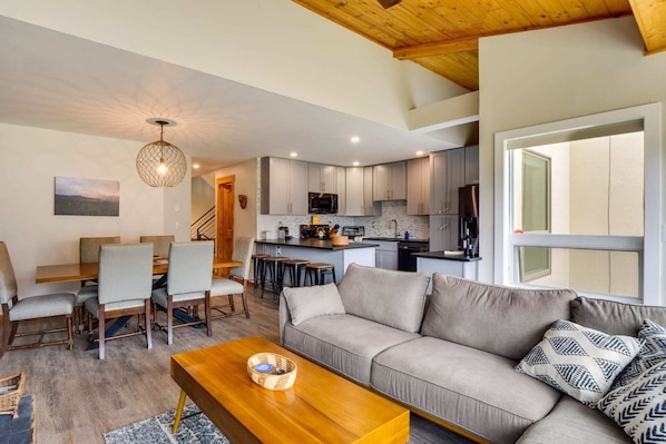 A modern living room with a sofa, coffee table, and dining area.