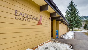 L’extérieur du complexe Eagle Valley Courts se distingue par sa façade en bois, son logo représentant un aigle rouge et le sol recouvert de neige.