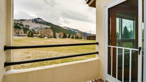 Un balcon donnant sur un paysage montagneux, un bâtiment doté d’une porte en verre et d’une rambarde en métal.