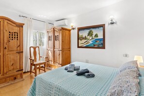 Une chambre à coucher avec un lit, une chaise, une armoire et un tableau au mur.