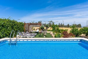 Une piscine avec des chaises longues et une pergola.