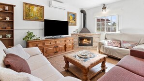 A living room with a fireplace, sofa, TV, and artwork. - Villa 'Los Arcos' with Pool, Mountain Views, Wi-Fi, and Air Conditioning (Alhaurín de la Torre)
