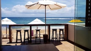 A balcony with a view of the beach, white umbrellas, and bar stools. - Pousada Manhã Dourada (Morro de São Paulo)