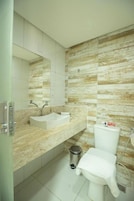 Un baño con lavamanos, espejo, inodoro y ducha.