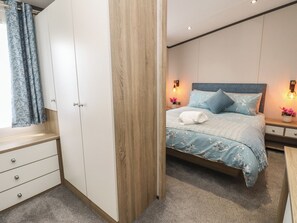 A bedroom with a bed, nightstands, a wardrobe, and a window with curtains.