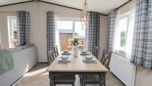 A dining area with a table set for four, a sofa, and a view of the outside.