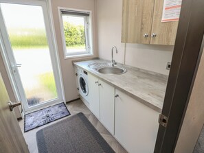 A compact kitchen with a washing machine, a sink, and a window. - 52 Parkview, Badger's Retreat (Richmond)