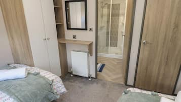 A bedroom with two beds, a radiator, a mirror, and a shower area.
