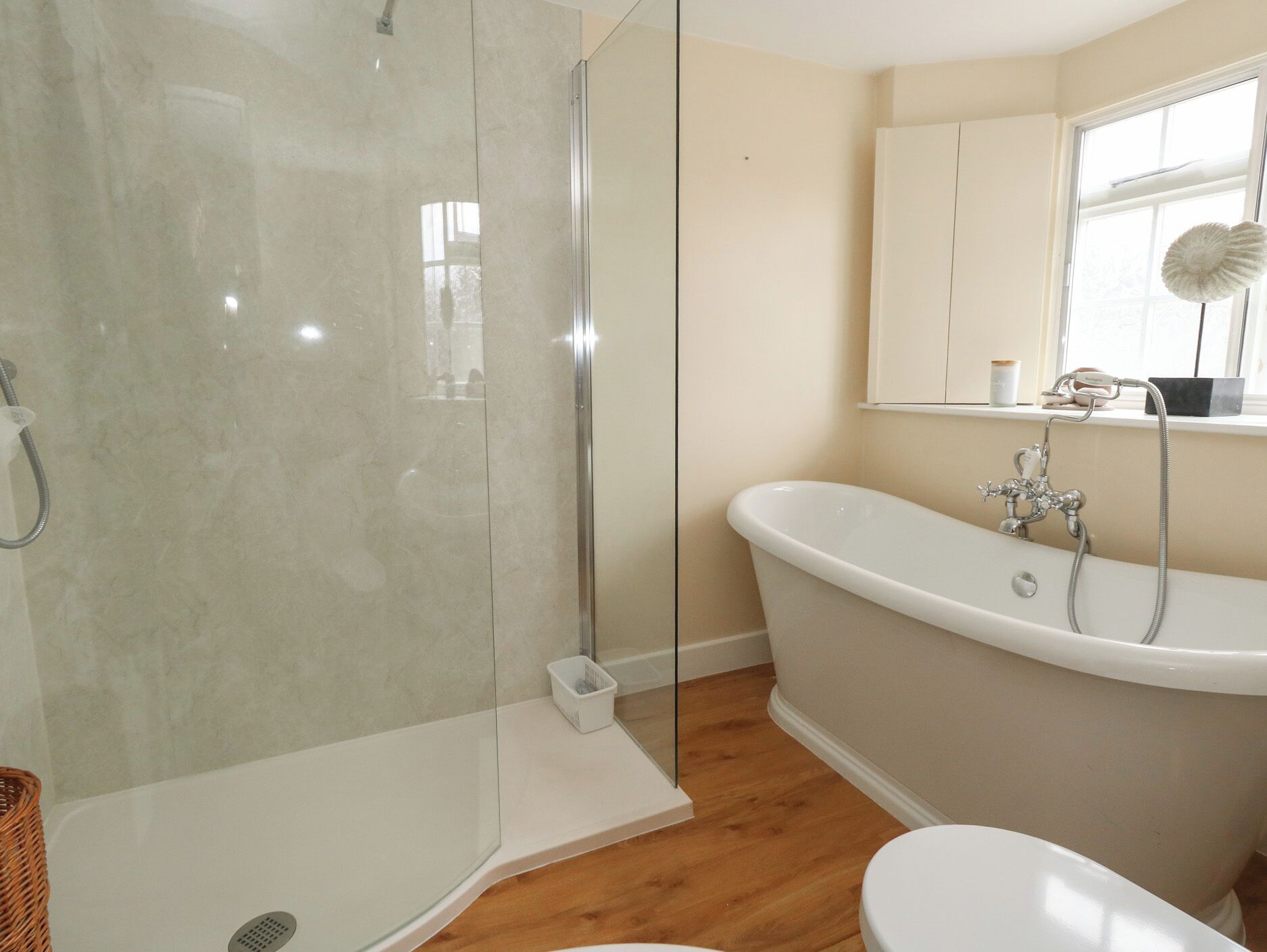 A bathroom with a glass-enclosed shower, a freestanding bathtub, and a toilet.