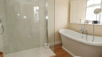 A bathroom with a glass-enclosed shower, a freestanding bathtub, and a toilet.