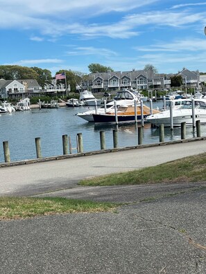 Ein Yachthafen mit vertäuten Booten, eine Uferpromenade und Wohnhäuser im Hintergrund.