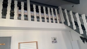 A room with a white ceiling, a wooden door, a window with horizontal blinds, and a wall-mounted light switch. - Rent studio 4 persons sea and city center (Le Grau-du-Roi)